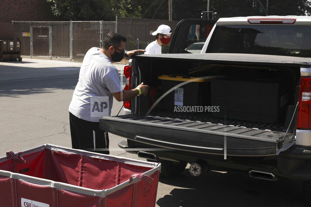 Joe Luevano, left, helps his son, Che Luevano, move out of Whitney Hall at California State University, Chico, Monday, Aug. 31, 2020, in Chico, Calif. California State University, Chico canceled its limited number of in-person classes Monday and told students in an urgently toned message to vacate campus housing by the weekend after nearly 30 people tested positive for the coronavirus days after the fall semester started. (Carin Dorghalli/Chico Enterprise-Record via AP)