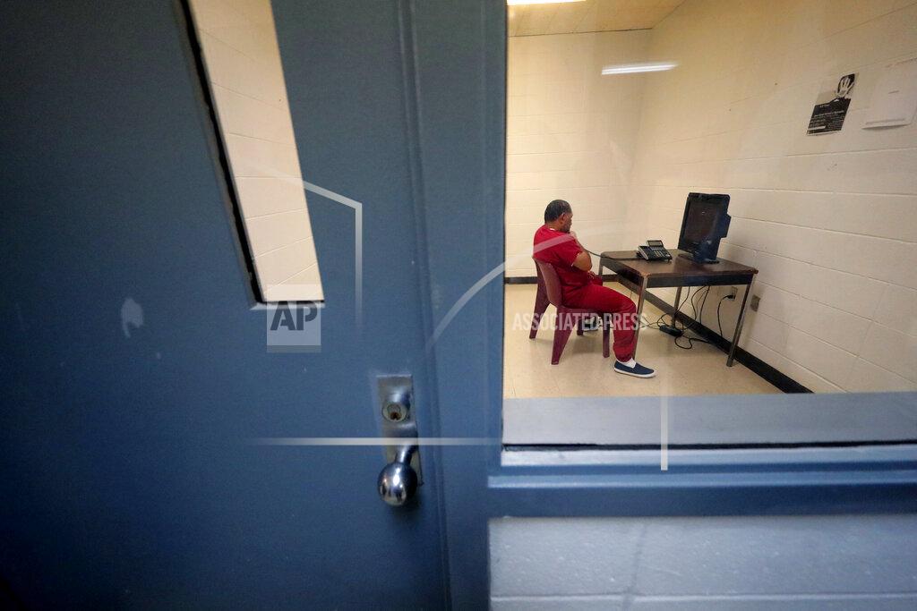 Gerald Herbert FILE — An immigration detainee sits in a room to use a telephone inside the Winn Correctional Center, in Winnfield, La., in this Sept. 26, 2019 file photo. The number of detainees nationwide has more than doubled since the end of February 2021, to nearly 27,000, according to recent data from U.S. Immigration and Customs Enforcement. (AP Photo/Gerald Herbert, File)
