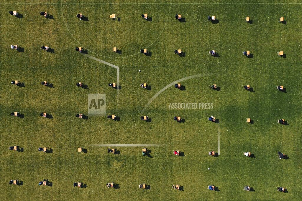 Hong Ki-Won Applicants take written examination during a recruitment test for Ansan Urban Corporation at the Wa stadium in Ansan, South Korea, Saturday, April 4, 2020. The corporation decided to held their recruitment test at the outdoor stadium as part of precaution against the new coronavirus and also all applicants had to wear face masks and had their temperature checked. South Korea on Saturday extended for two weeks guidelines urging people to stick to social distancing. (Hong Ki-won/Yonhap via AP)