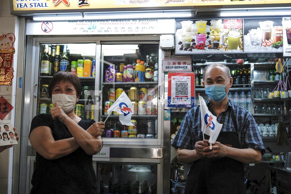 Ee Ming Toh Shopkeepers at Bedok South market hold miniature flags of the People's Action Party during the final day of the election campaign Wednesday, July 8, 2020, in Singapore. Singaporeans go to the polls on July 10 in Southeast Asia's first election since the coronavirus pandemic began, with the health crisis and an economic recession expected to bolster Prime Minister Lee Hsien Loong's party and extend its unbroken rule. (AP Photo/Ee Ming Toh)