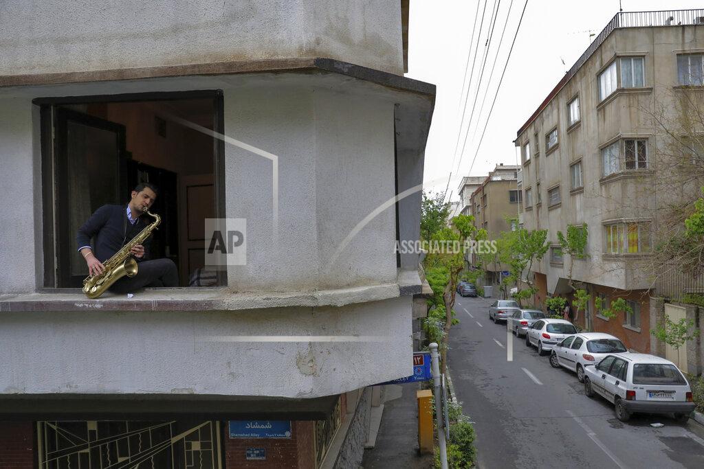 Ebrahim Noroozi Mohammad Maleklee, 23, of the National Orchestra of Iran and Tehran Symphony, plays saxophone from his window, during mandatory self-isolation due to the new coronavirus disease outbreak, in Tehran, Iran on Wednesday, April 8, 2020 photo. With performance halls closed, musicians find performance spaces wherever they can. (AP Photo/Ebrahim Noroozi)