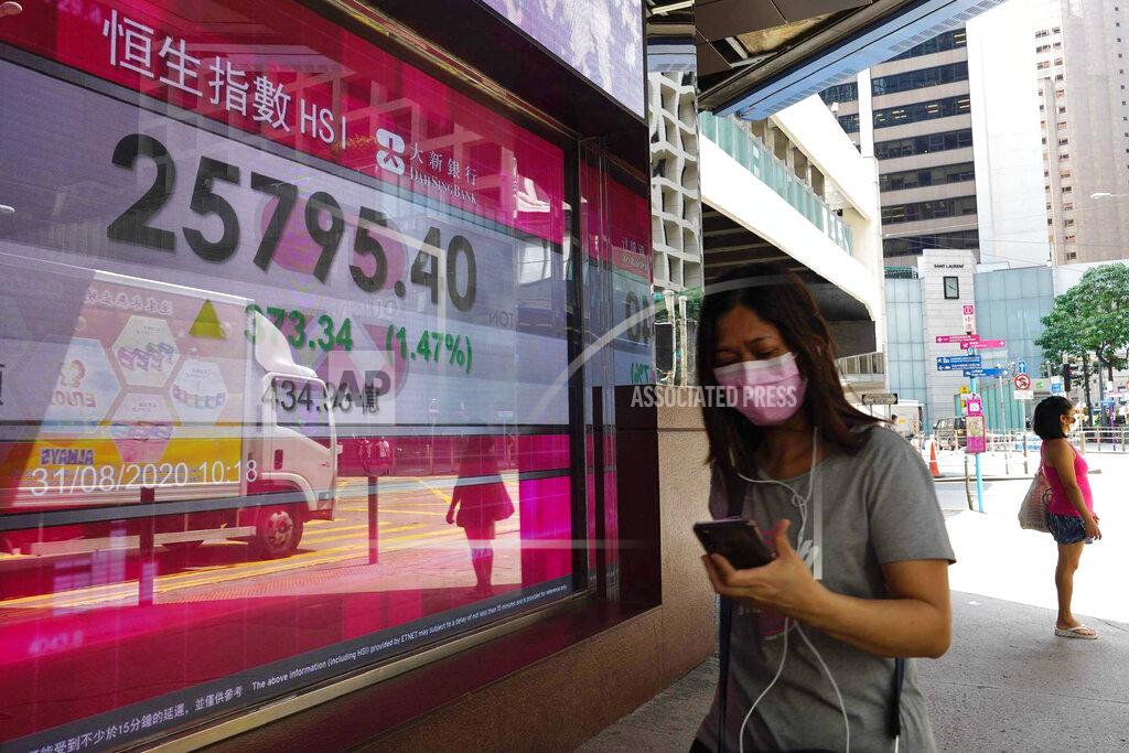 A woman walks past a bank electronic board showing the Hong Kong share index outside a Hong Kong local bank Monday, Aug. 31, 2020. Asian stock markets have risen after Wall Street turned in its fifth straight weekly gain and China’s manufacturing growth held steady.(AP Photo/Vincent Yu)