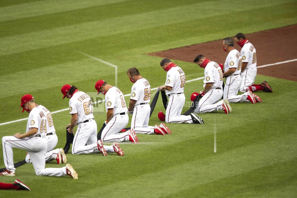 Alex Brandon Members of Washington Nationals kneel and hold a piece of black fabric before an opening day baseball game against the New York Yankees at Nationals Park, Thursday, July 23, 2020, in Washington. (AP Photo/Alex Brandon)