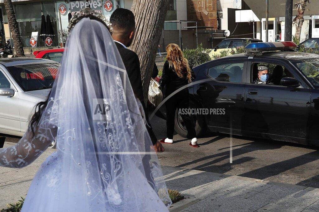 Hussein Malla FILE - In this April 18, 2020 file photo, a policeman asks a bride and groom to leave the waterfront promenade where they had decided to take some pictures, in Beirut, Lebanon. In a region where marriage is the cornerstone of society, couples are plowing ahead with weddings, despite the deadly risks. From the Palestinian territories to the United Arab Emirates, officials attribute a spike in coronavirus cases to traditional, large-scale weddings that flout public health restrictions. (AP Photo/Hussein Malla, File)