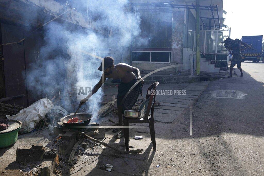 Eranga Jayawardena A man cooks food with firewood for his roadside eatery, amid shortage of cooking gas in Colombo, Sri Lanka, Thursday, June 23, 2022. Sri Lanka's prime minister says the island nation's debt-laden economy has "collapsed" as it runs out of money to pay for food and fuel. (AP Photo/Eranga Jayawardena)