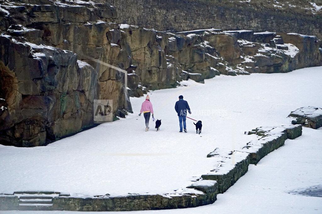 Owen Humphreys People walk with dogs after more snow fell overnight near Cullercoats on the north east coast of England, Friday Feb. 12, 2021. A cold snap continues to grip much of the nation Friday. (Owen Humphreys/PA via AP)