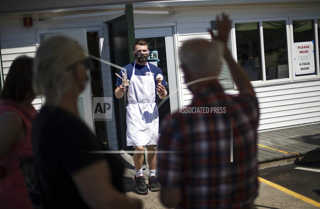 David Goldman Brendan Kenny serves customers with masks at a Brickley's Ice Cream shop, one of two stores, in Narragansett, R.I., Wednesday, July 29, 2020. The other nearby location closed when teenage workers were harassed by customers who refused to wear a mask or socially distance. Disputes over masks and mask mandates are playing out at businesses, on public transportation and in public places across America and other nations. (AP Photo/David Goldman)
