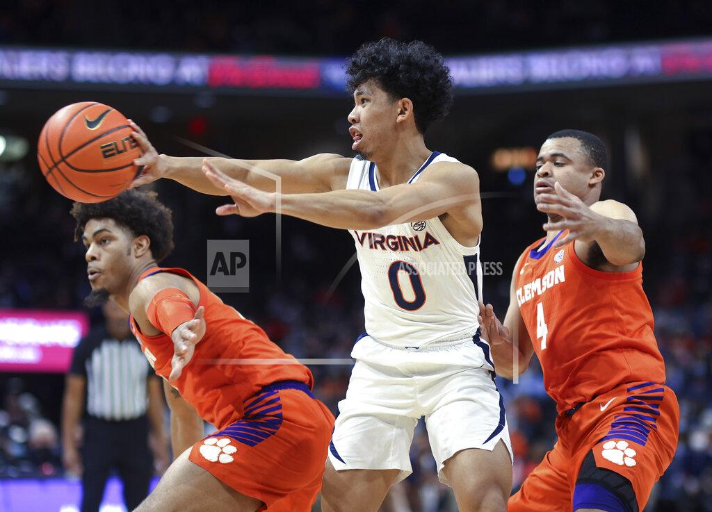 Andrew Shurtleff Virginia guard Kihei Clark (0) passes the ball away from Clemson guard David Collins and guard Nick Honor (4) during the first half of an NCAA college basketball game in Charlottesville, Va., Wednesday, Dec. 22, 2021. (AP Photo/Andrew Shurtleff)