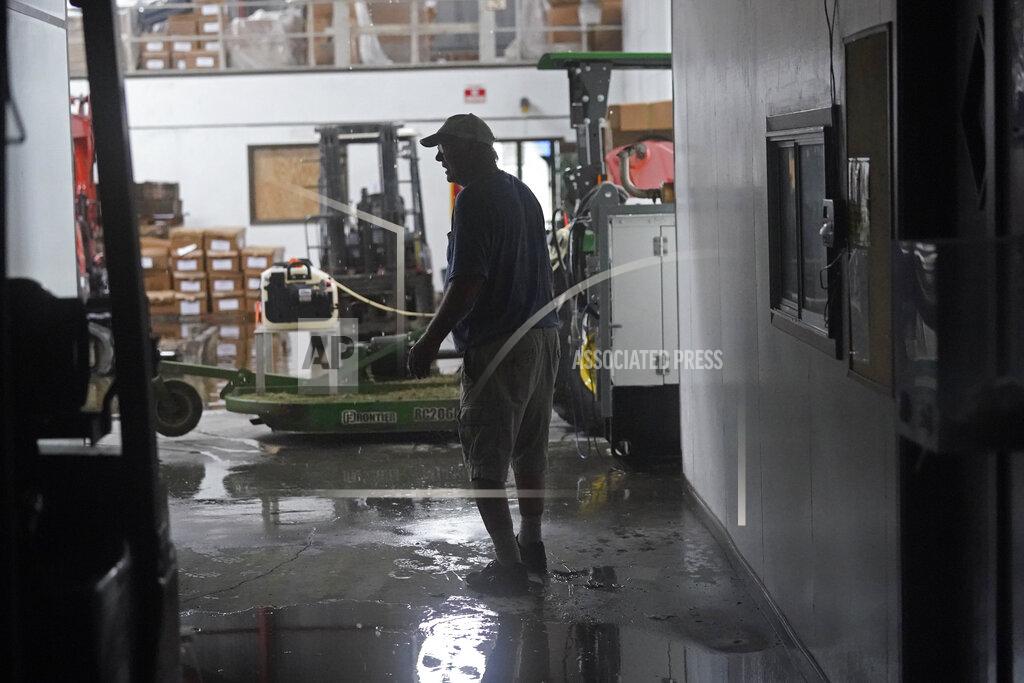 Gerald Herbert Steven Voisin walks through his family's heavily damaged oyster processing plant, as rain from Tropical Storm Nicholas, currently in the Gulf of Mexico, comes down through a destroyed roof, in the aftermath of Hurricane Ida in Houma, La., Tuesday, Sept. 14, 2021. (AP Photo/Gerald Herbert)