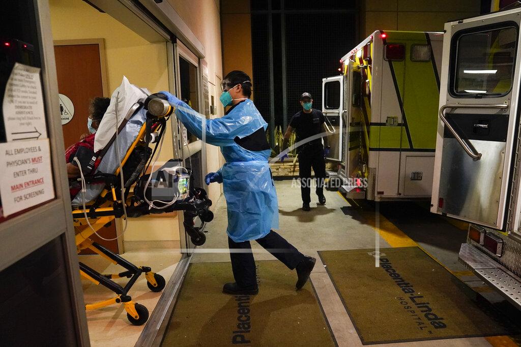 Jae C. Hong Emergency medical technician Thomas Hoang, 29, of Emergency Ambulance Service, pushes a gurney into an emergency room to drop off a COVID-19 patient in Placentia, Calif., Friday, Jan. 8, 2021. EMTs and paramedics have always dealt with life and death — they make split-second decisions about patient care, which hospital to race to, the best and fastest way to save someone — and now they're just a breath away from becoming the patient themselves. (AP Photo/Jae C. Hong)