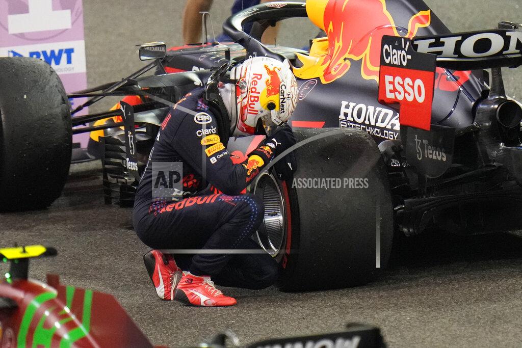 Red Bull driver Max Verstappen of the Netherlands kneels next to his car after he became the world champion after winning the Formula One Abu Dhabi Grand Prix in Abu Dhabi, United Arab Emirates, Sunday, Dec. 12, 2021. (AP Photo/Hassan Ammar)