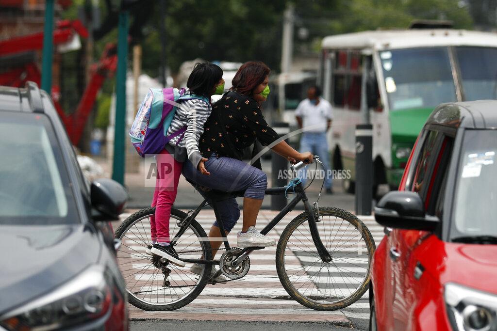 Rebecca Blackwell A woman and a child, both wearing face masks, ride a bike in the Xochimilco district of Mexico City, Thursday, May 7, 2020. Health authorities concede that the real number of COVID-19 infections in the densely populated capital is many times higher than the official count, and authorities and experts agree that the worst is yet to come. (AP Photo/Rebecca Blackwell)