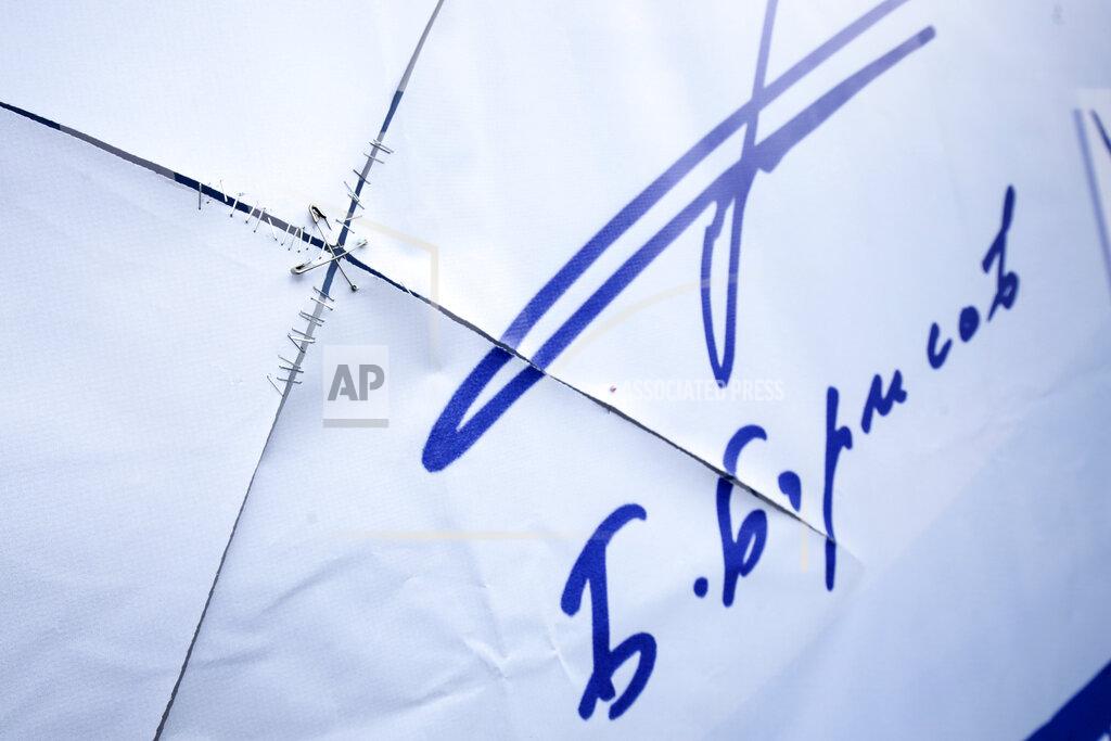 Valentina Petrova Pins hold together a poster carrying the signature of Bulgarian prime minister Boyko Borissov in Sofia, Bulgaria, Wednesday, March 31, 2021. After months of nationwide anti-government protests over corruption, stalled reforms and a stagnating economy in the EU's poorest member state, Bulgarians are gearing up for a parliamentary election overshadowed by a deadly pandemic. (AP Photo/Valentina Petrova)