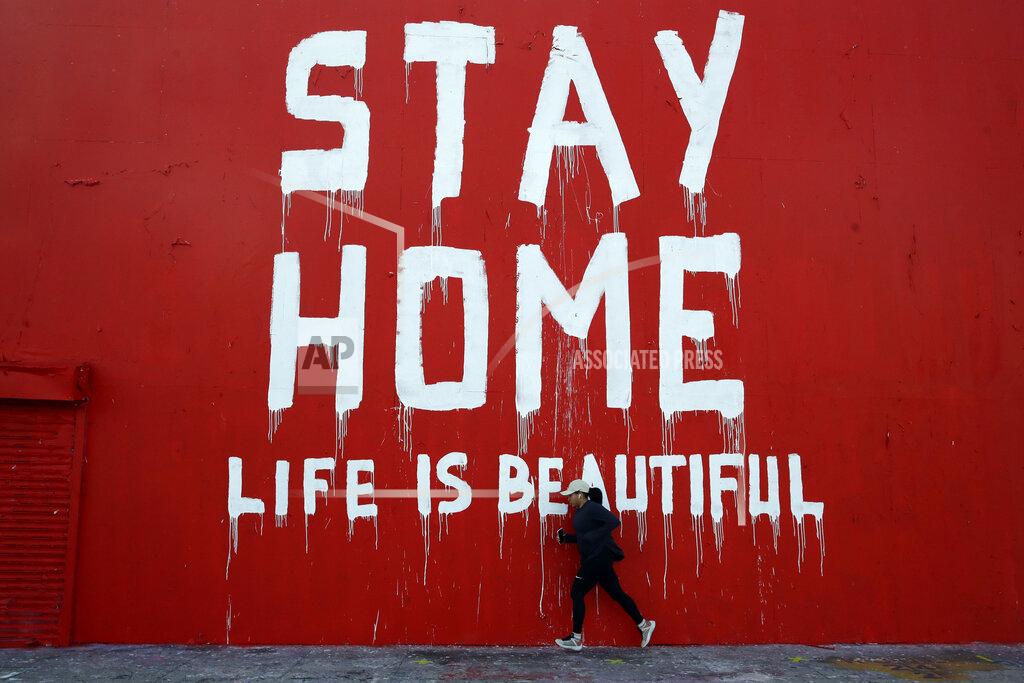 Marcio Jose Sanchez A jogger runs by a mural which reads "Stay at Home, Life is Beautiful" Thursday, April 2, 2020, in Los Angeles. California is in its second week of a statewide lockdown, where schools and nonessential businesses are closed and the governor has ordered people to stay home. (AP Photo/Marcio Jose Sanchez)