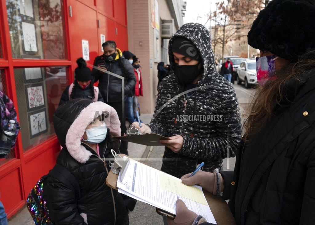 Mark Lennihan A parent, center, completes a form granting permission for random COVID-19 testing for students as he arrives with his daughter, left, at P.S. 134 Henrietta Szold Elementary School, Monday, Dec. 7, 2020, in New York. Public schools reopened for in-school learning Monday after being closed since mid-November. (AP Photo/Mark Lennihan)