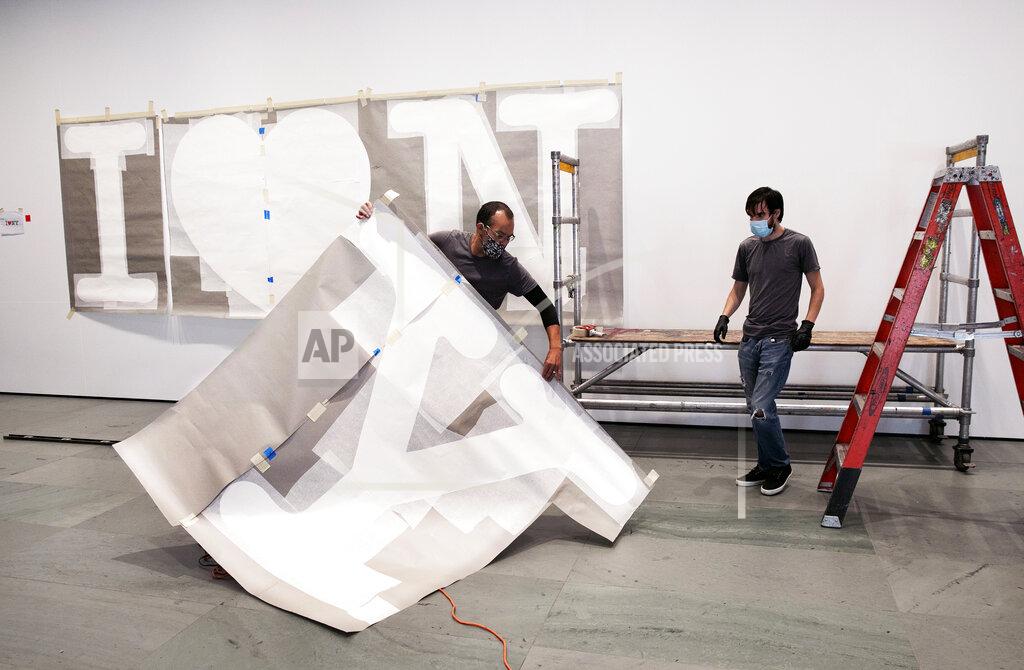 Mark Lennihan George Vealsquez, left, and Charles Lester install templates for "I Love NY" at the entrance to the Museum of Modern Art, Thursday, Aug. 20, 2020, in New York. The work by graphic designer Milton Glaser will be done in red for the heart and black for the lettering. MOMA reopens Aug. 27, 2020. (AP Photo/Mark Lennihan)
