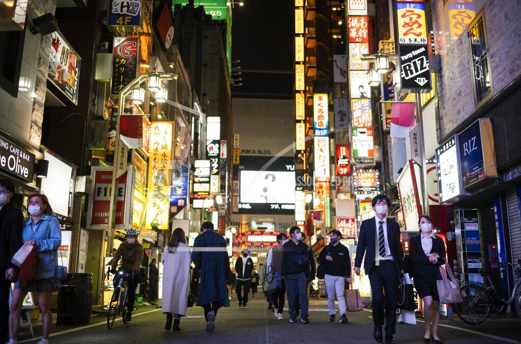 Hiro Komae People walk through a street filled with entertainment, restaurants and bars in the Shinjuku neighborhood of Tokyo on Friday, April 9, 2021. Japan announced Friday that it will raise the coronavirus alert level in Tokyo to allow tougher measures to curb the rapid spread of a more contagious variant ahead of the Summer Olympics. (AP Photo/Hiro Komae)