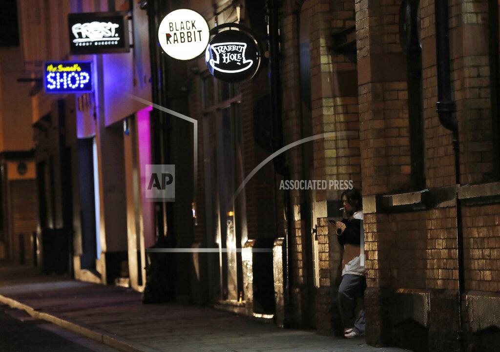 Frank Augstein A person smokes a cigarette on a street full of closed bars and pubs in Liverpool, England, Wednesday, Oct. 14, 2020. As the first area in England slapped with strict new restrictions to curb the resurgent coronavirus that have shuttered pubs and imperiled thousands of jobs, Liverpool again feels it's being punished by policies made in Britain's capital, 180 miles (290 kilometers) to the south. (AP Photo/Frank Augstein)