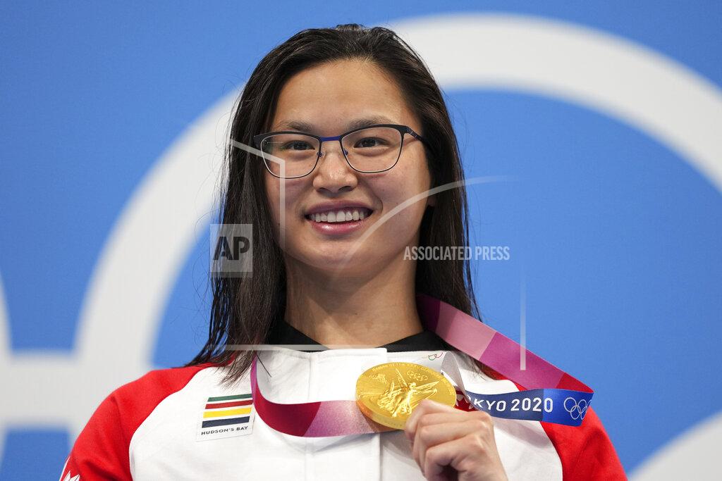 Matthias Schrader Margaret MacNeil of Canada celebrates on the podium after winning the women's 100-meter butterfly final at the 2020 Summer Olympics, Monday, July 26, 2021, in Tokyo, Japan. (AP Photo/Matthias Schrader)