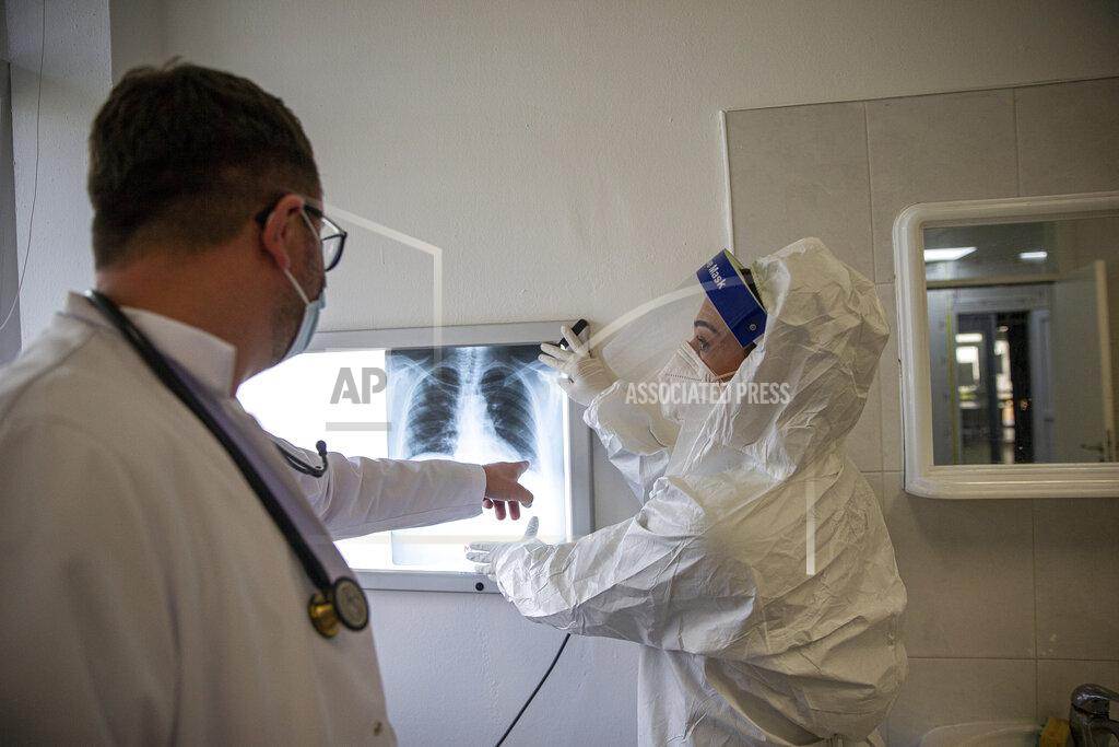 Soprano singer Arta Jashari, right, assists pulmonologist Flamur Marku at the Pulmonological Clinic in Kosovo's capital Pristina, Monday, March 8, 2021. Jashari, a well-known and much-loved soprano in Kosovo, could hardly forget her neighbors’ assistance while in quarantine helping her father cope with the virus. That prompted her do the same thing to others, turning herself regularly to the hospital to help staff and patients’ families to cope with the virus pandemic. (AP Photo/Visar Kryeziu)