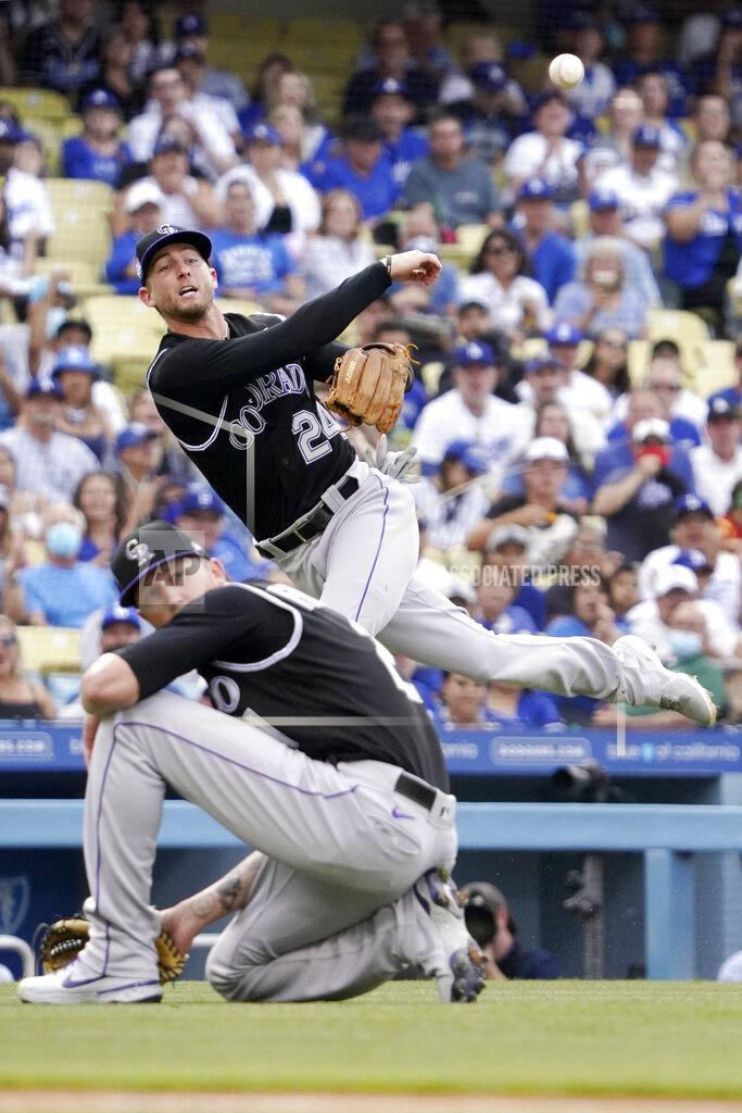Mark J. Terrill Colorado Rockies second baseman Ryan McMahon, top, attempts to throw out Los Angeles Dodgers' Chris Taylor at first as starting pitcher Kyle Freeland watches during the first inning of a baseball game Saturday, July 24, 2021, in Los Angeles. Taylor was safe at first on the play. (AP Photo/Mark J. Terrill)