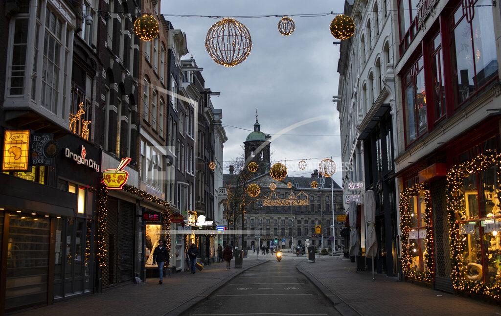 Peter Dejong FILE- In this Thursday, Jan. 14, 2021, file photo, closed stores on Dam street and the Royal Palace on Dam Square, rear, are seen in Amsterdam. The Dutch government said Wednesday, Jan. 20, 2021, that it wants to impose a curfew as part of beefed-up restrictions to rein in the spread of new more contagious variants of the coronavirus that already accounts for at least one in every 10 Dutch infections. (AP Photo/Peter Dejong, File)