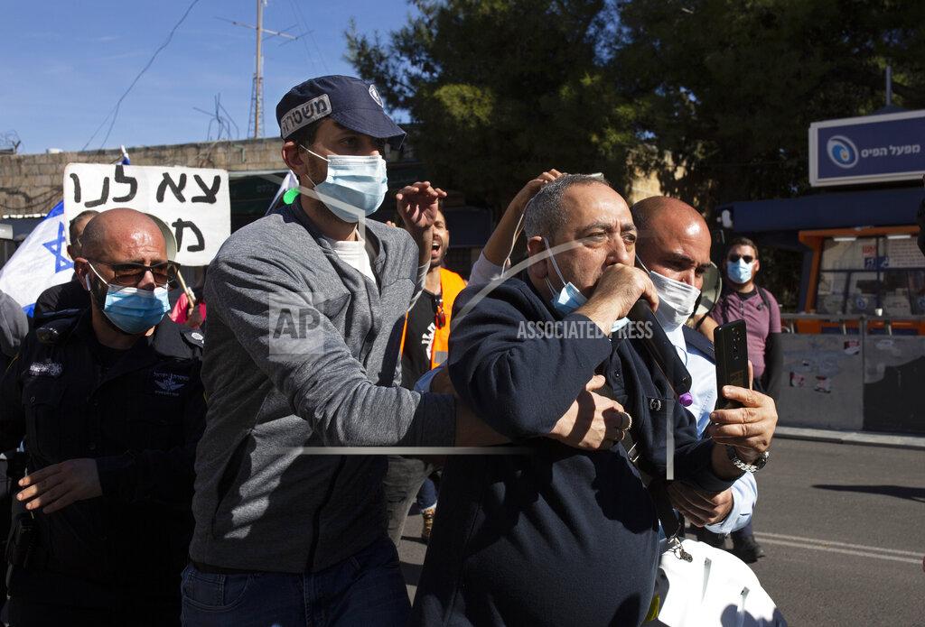Maya Alleruzzo A supporter of Israeli Israeli Prime Minister Benjamin Netanyahu is led away by a plainclothes police officers after a scuffle with anti-Netanyahu protesters outside the District Court during Netanyahu's corruption trial, in Jerusalem, Monday, Feb. 8, 2021. Netanyahu has pleaded not guilty as his trial on corruption charges resumes in a Jerusalem courtroom just weeks before national elections in which he hopes to extend his 12-year rule. (AP Photo/Maya Alleruzzo)