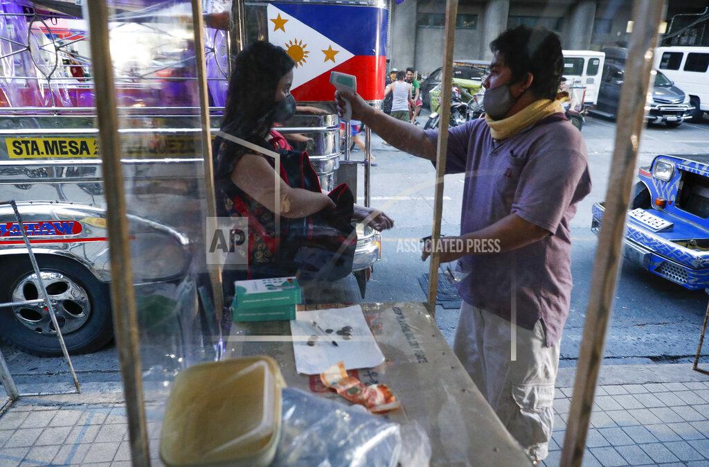 Aaron Favila A passenger has her temperature checked to prevent the spread of the new coronavirus as some routes for the Traditional Jeepney buses were opened to help public transportation while the government slowly eases lockdown in metropolitan Manila, Philippines on Friday, July 3, 2020. (AP Photo/Aaron Favila)