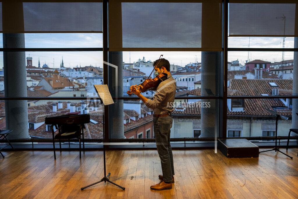 A musician in a face mask plays the violin at a rehearsal at the Teatro Real in Madrid, Spain, Friday, Nov. 13, 2020. The theater is one of the few major opera houses that have reopened during the pandemic, although to smaller audiences. (AP Photo/Bernat Armangue)