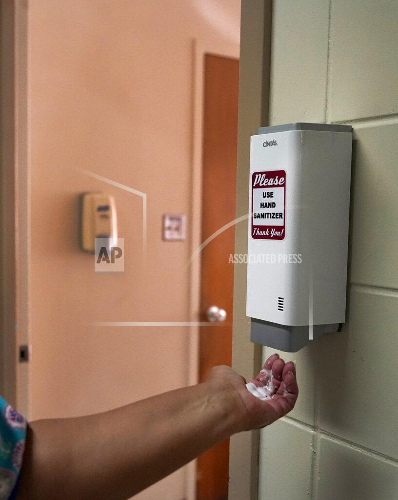 Charles Rex Arbogast Roseland Community Hospital RN Rhonda Jones gets her hand sanitized Friday, Jan. 29, 2021, at the South Side of Chicago hospital. Jones has treated many patients with severe COVID-19, a relative died from it, and her mother and a nephew were infected and recovered, but she is still holding out getting the vaccine. (AP Photo/Charles Rex Arbogast)