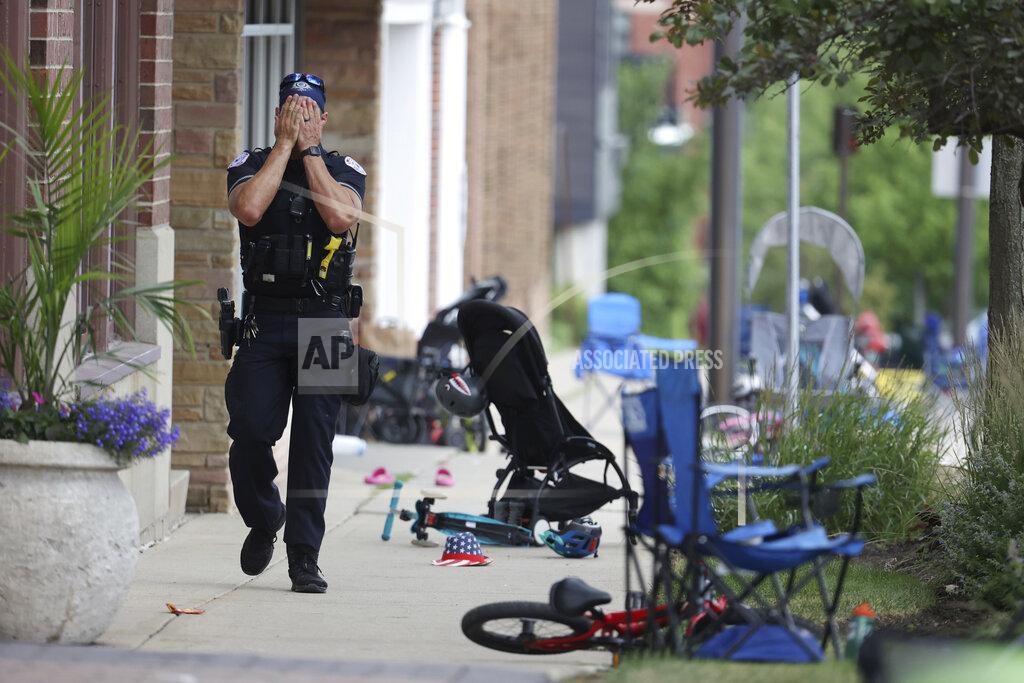 Brian Cassella A Lake County police officer walks down Central Ave in Highland Park, Ill. on Monday, July 4, 2022, after a shooter fired on the northern suburb's Fourth of July parade. (Brian Cassella/Chicago Tribune via AP)