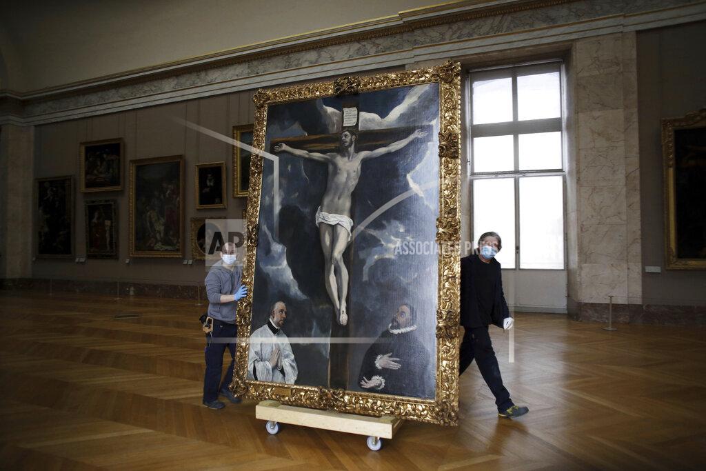 Thibault Camus Workers at the Louvre museum transport a painting called 'Christ on the Cross Adored by Two Donors' by Spanish painter El Greco, as it returns from an exhibition at the Chicago Institute, in the Louvre museum, in Paris, Tuesday, Feb. 9, 2021. (AP Photo/Thibault Camus)