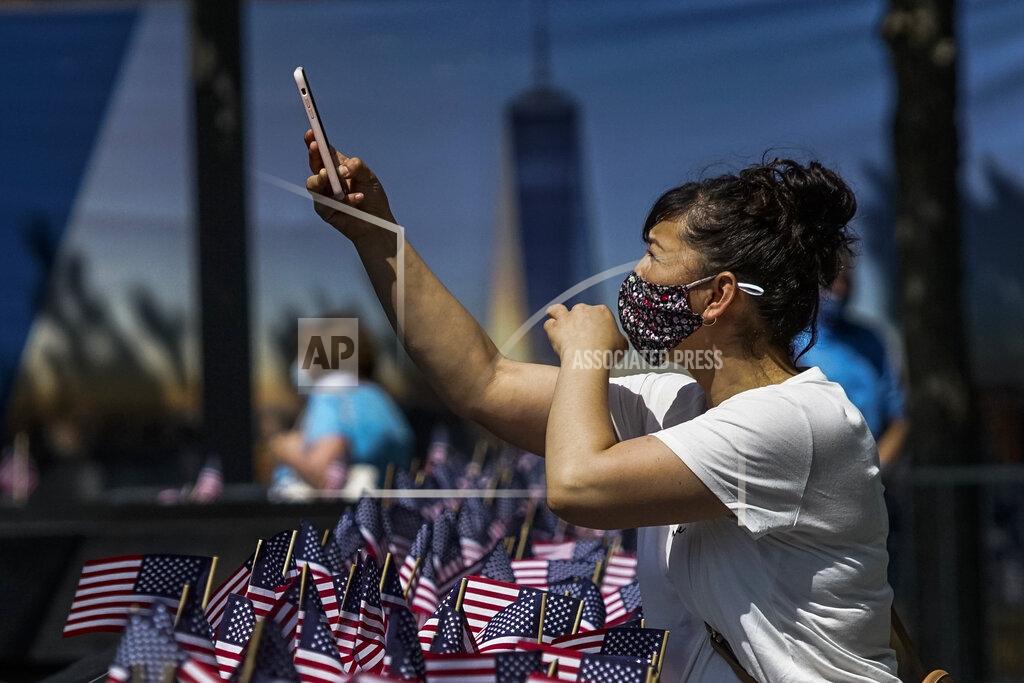 Eduardo Munoz Alvarez A woman takes pictures with her phone as people visit the 9/11 Memorial Plaza during its reopening after having been closed for more than three months amid the coronavirus pandemic, Saturday, July 4, 2020, in New York. (AP Photo/Eduardo Munoz Alvarez)