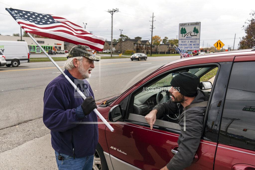 David Goldman A passing motorist at right argues with Trump supporter Mike Jamerson, left, during a rally at an intersection in Mount Clemens, Mich., Thursday, Oct. 29, 2020. As the traditional Election Day closes in, Americans are exhausted from constant crises, on edge because of volatile political divisions and anxious about what will happen next. (AP Photo/David Goldman)