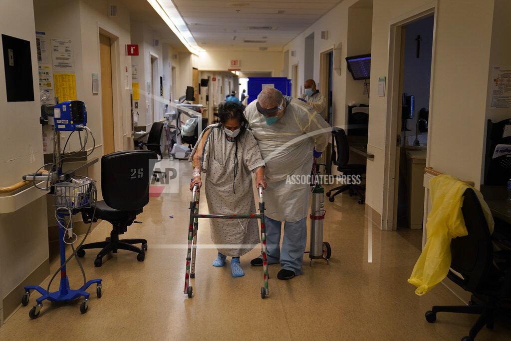 Jae C. Hong FILE - In this Dec. 22, 2020 file photo Physical therapist Alireza Akbarpour, right, helps Maria Herrera exercise in a COVID-19 unit at Providence Holy Cross Medical Center in the Mission Hills section of Los Angeles. California became the first state to record 2 million confirmed coronavirus cases, reaching the milestone on Christmas Eve as close to the entire state was under a strict stay-at-home order and hospitals were flooded with the largest crush of cases since the pandemic began. (AP Photo/Jae C. Hong,File)