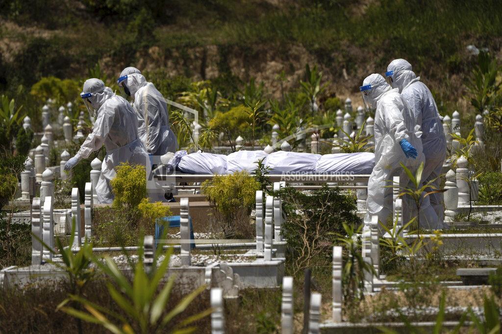 Vincent Thian In this Feb. 5, 2021, file photo, workers wearing personal protective equipment (PPE) carry the body of a victim of the coronavirus disease at a Muslim cemetery in Gombak on the outskirts of Kuala Lumpur, Malaysia. Images of bodies burning in open-air pyres during the peak of the pandemic in India horrified the world in May, but in the last two weeks Malaysia and two other Southeast Asian nations have surpassed India’s peak per capita death rate as a new coronavirus wave tightens its grip on the region. (AP Photo/Vincent Thian, File)