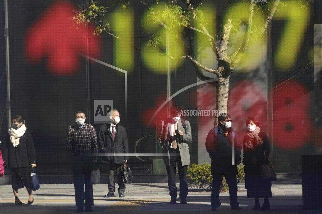 Koji Sasahara People are reflected on the electronic board of a securities firm in Tokyo, Wednesday, Jan. 20, 2021. Asian shares were mostly higher Wednesday, ahead of Joe Biden's inauguration as president, ending President Donald Trump’s four-year term. Japan's benchmark lost early gains as worries grew about the surge in coronavirus cases. (AP Photo/Koji Sasahara)
