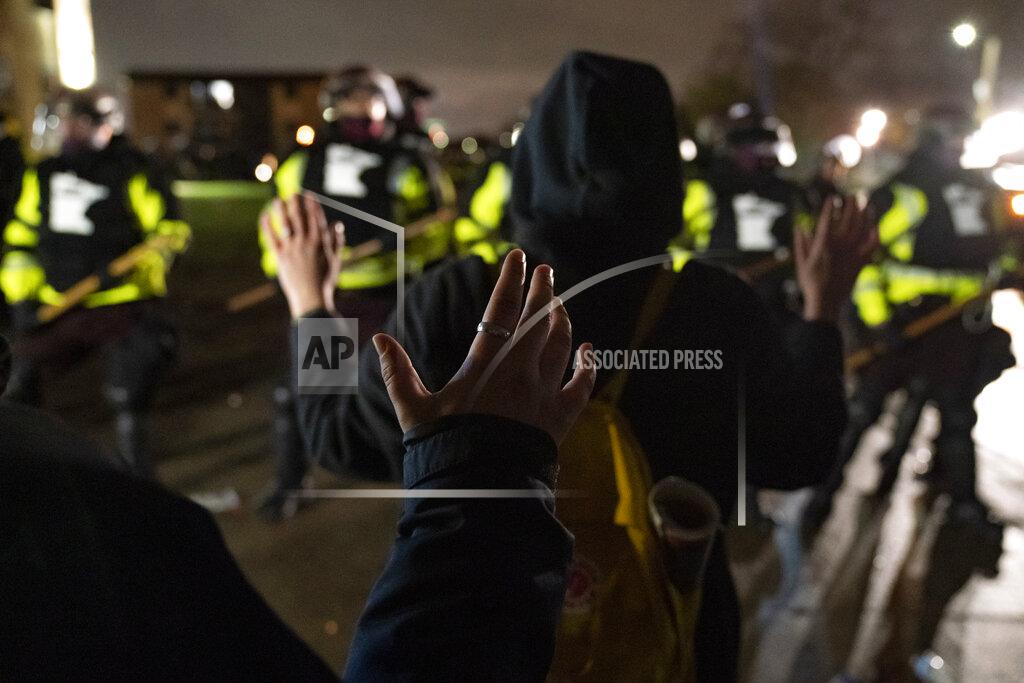 John Minchillo Demonstrators raise their hands while facing off against a perimeter of police as they defy an order to disperse during a protest against the police shooting of Daunte Wright, late Monday, April 12, 2021, in Brooklyn Center, Minn. (AP Photo/John Minchillo)