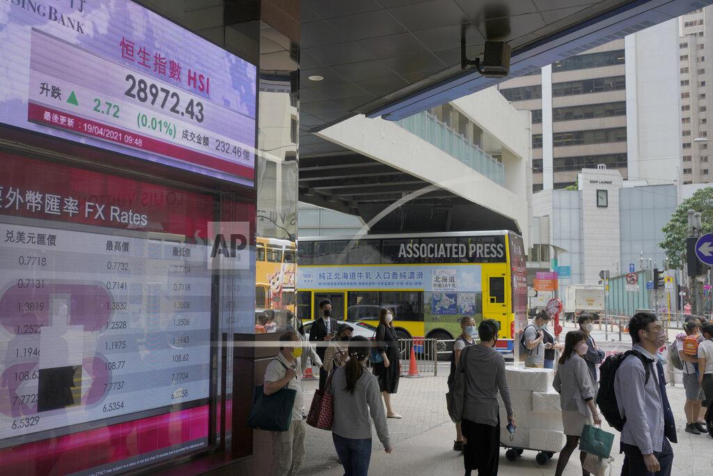 Vincent Yu People walk past a bank's electronic board showing the Hong Kong share index at Hong Kong Stock Exchange in Hong Kong Monday, April 19, 2021. Asian shares were mixed Monday amid cautious optimism about a global rebound from the coronavirus pandemic. (AP Photo/Vincent Yu)