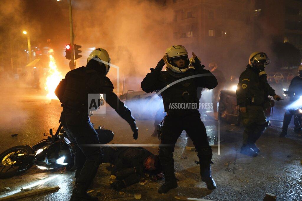 Aggelos Barai A policeman lays injured on the road as his colleagues react during clashes in Athens, Tuesday, March 9, 2021. Severe clashes broke out Tuesday in Athens after youths protesting an incident of police violence attacked a police station with petrol bombs, and severely injured one officer. (AP Photo/Aggelos Barai)