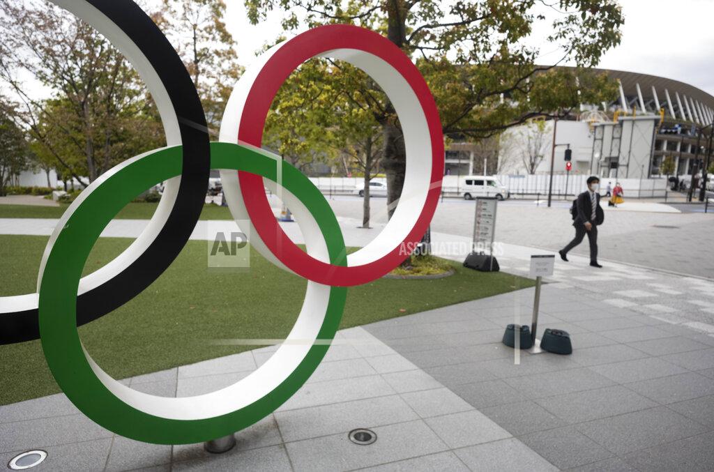 Hiro Komae A man walks by a part of Olympic rings displayed at the Japan Olympic Museum situated across from the Japan National Stadium planned to be used for the postponed Tokyo 2020 Olympic Games in Tokyo Friday, April 2, 2021. Many preparations are still up in the air as organizers try to figure out how to hold the postponed games in the middle of a pandemic. (AP Photo/Hiro Komae)