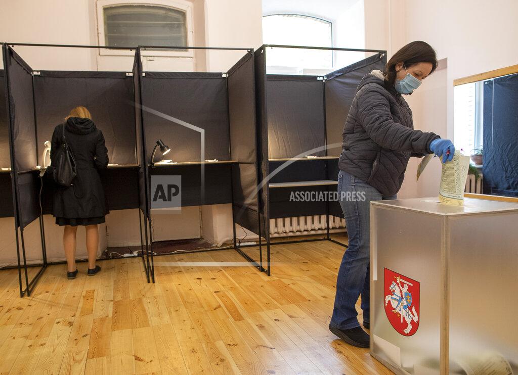 Mindaugas Kulbis A woman, wearing a face mask to protect against coronavirus, casts her ballot at a polling station during parliamentary elections in Vilnius, Lithuania, Sunday, Oct. 11, 2020. Polls opened Sunday for the first round of national election in Lithuania, where voters will renew the 141-seat parliament and the ruling four-party coalition is widely expected to face a stiff challenge from the opposition to remain in office. (AP Photo/Mindaugas Kulbis)