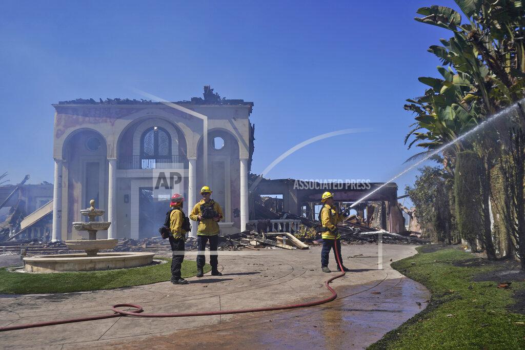 Marcio Jose Sanchez Members of the Torrance Fire Dept, from left, Brent Nunez, Michael Cotter and Rick Cathey protect the remains of a fire-damaged home in the aftermath of the Coastal Fire Thursday, May 12, 2022, in Laguna Niguel, Calif. (AP Photo/Marcio Jose Sanchez)