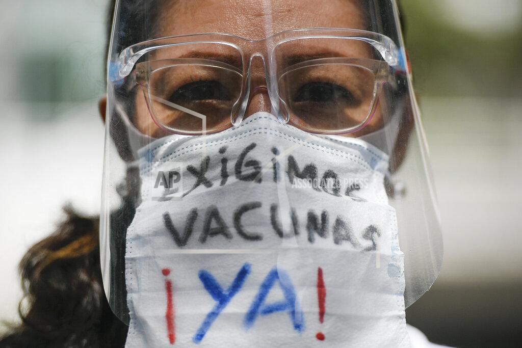 Matias Delacroix A healthcare worker, wearing a protective face mask with a message that reads in Spanish: "We demand vaccines now!", attends a march demanding a more equitable and faster distribution of COVID-19 vaccines, in the Los Palos Grandes neighborhood of Caracas, Venezuela, Saturday, April 17, 2021. (AP Photo/Matias Delacroix)