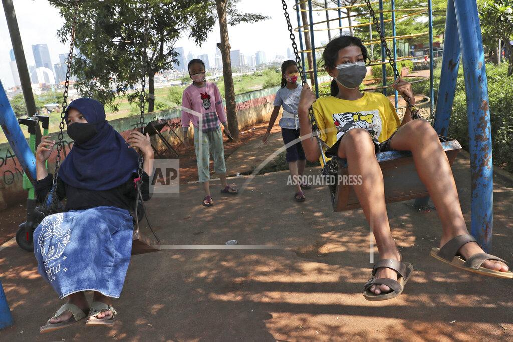 Tatan Syuflana Indonesian children wearing face masks as a precaution against coronavirus outbreak play on swings in Jakarta, Indonesia, Wednesday, Sept. 23, 2020. (AP Photo/Tatan Syuflana)