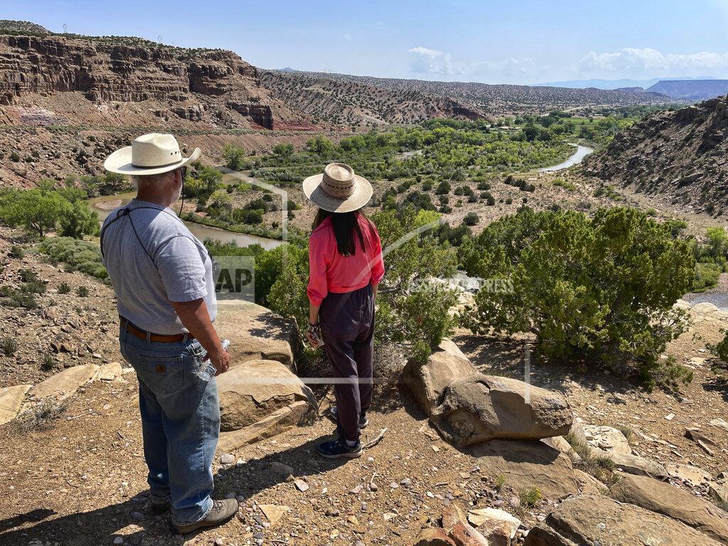 Susan Montoya Bryan This Aug. 31, 2021 photo shows U.S. Rep. Teresa Leger Fernández, center, surveying the Rio Chama valley near Abiquiu, New Mexico, as Tim Seaman with the Rio Chama Acequia Association looks on. The traditional irrigation systems known as acequias are feeling more pressure as drought persists and climate change piles on with warmer temperatures. (AP Photo/Susan Montoya Bryan)