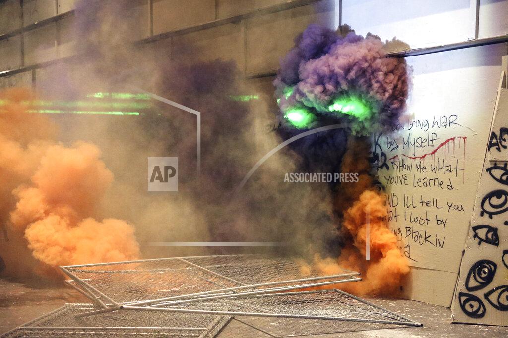 Dave Killen Smoke fills the street as police respond to protesters during a demonstration, Friday, July 17, 2020 in Portland, Ore. Militarized federal agents deployed by the president to Portland, fired tear gas against protesters again overnight as the city’s mayor demanded that the agents be removed and as the state’s attorney general vowed to seek a restraining order against them. (Dave Killen/The Oregonian via AP)