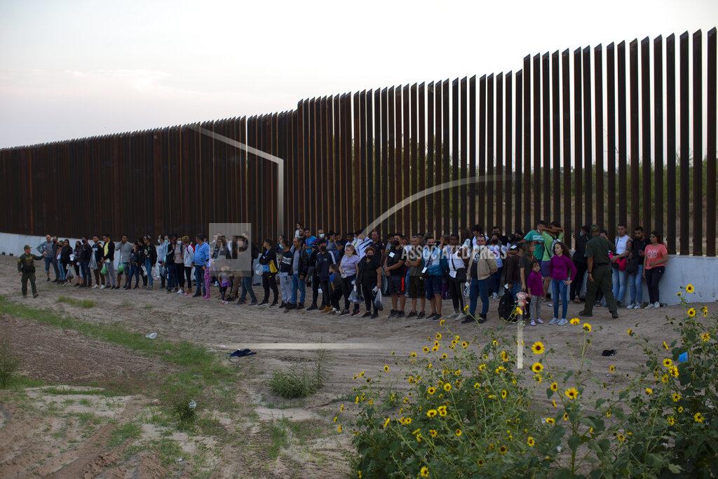 Dario Lopez-Mills A group of migrants stand next to the border wall as they wait to get taken away by the Border Patrol in Eagle Pass, Texas, Saturday, May 21, 2022. The Eagle Pass area has become increasingly a popular crossing corridor for migrants, especially those from outside Mexico and Central America, under Title 42 authority, which expels migrants without a chance to seek asylum on grounds of preventing the spread of COVID-19. (AP Photo/Dario Lopez-Mills)