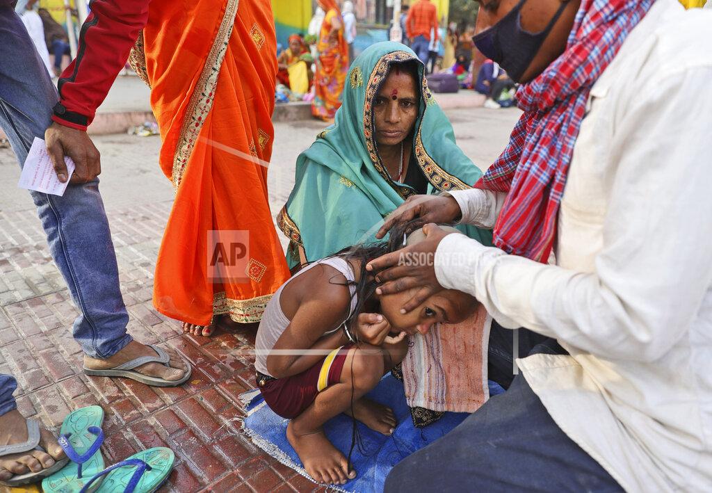 Karma Sonam A family get their son head tonsured during Kumbh mela, in Haridwar in the Indian state of Uttarakhand, Monday, April 12, 2021. As states across India are declaring some version of a lockdown to battle rising Covid cases as part of a nationwide second-wave, thousands of pilgrims are gathering on the banks of the river Ganga for the Hindu festival Kumbh Mela. The faithful believe that a dip in the waters of the Ganga will absolve them of their sins and deliver them from the cycle of birth and death. (AP Photo/Karma Sonam)