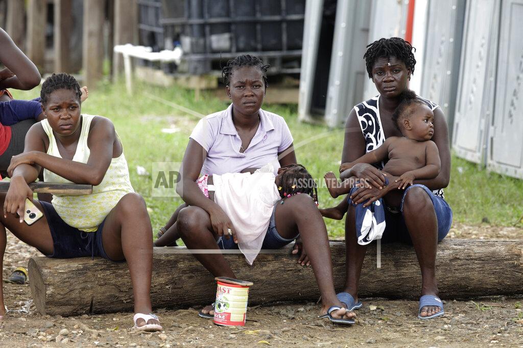 Arnulfo Franco Women with children sit on a log at a migrant camp in Lajas Blancas, Darien province, Panama, Saturday, Aug. 29, 2020. Panama, a transit point for virtually every migrant heading from South America to the United States, closed its borders on March 16 to halt the spread of COVID-19. (AP Photo/Arnulfo Franco)